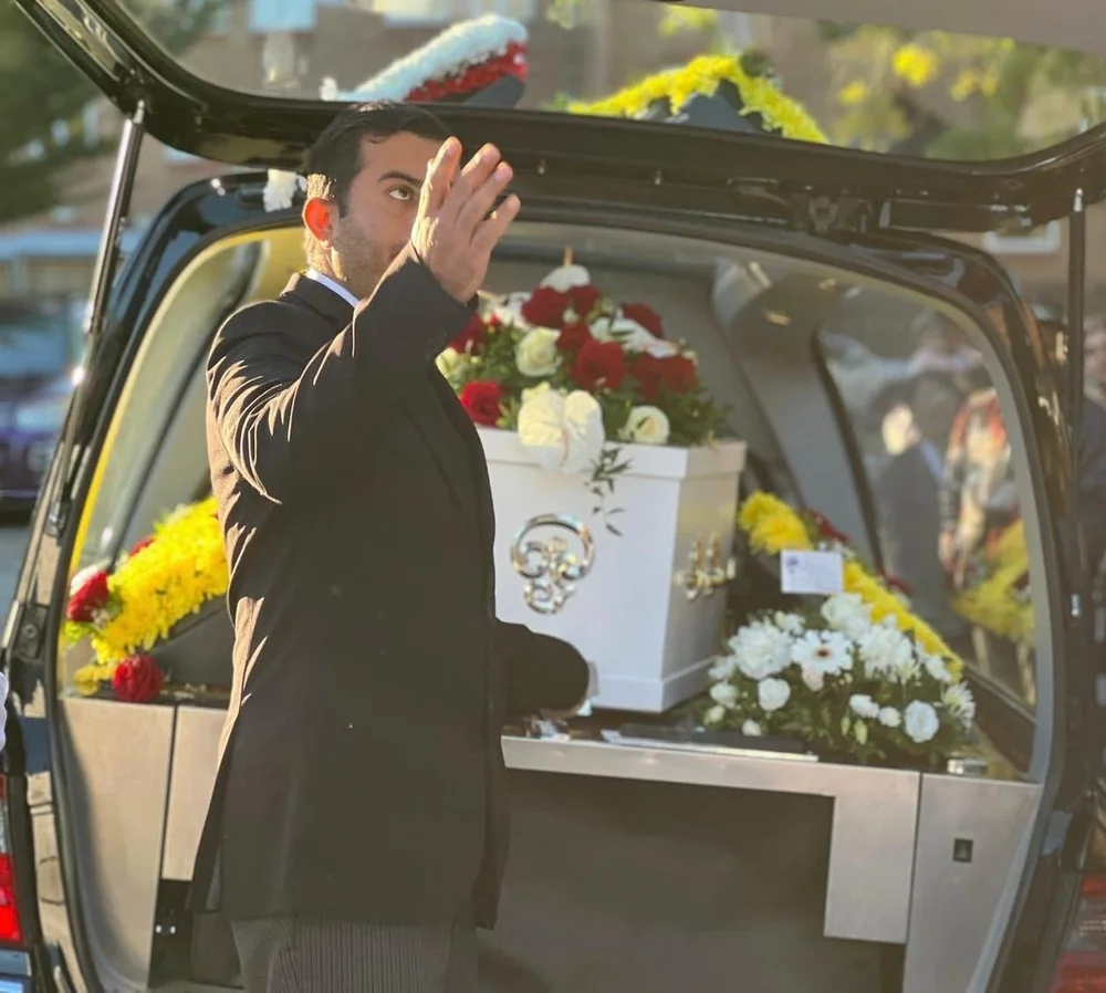 Dignified funeral director arranging flowers inside the hearse