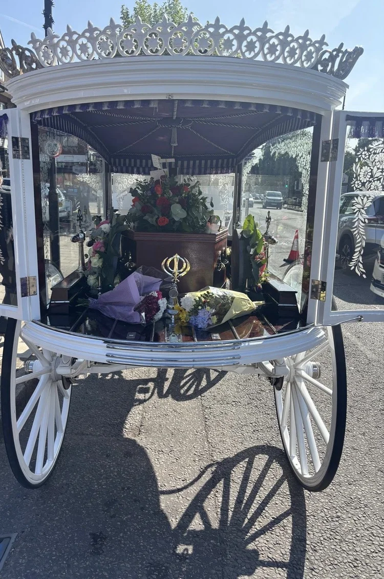 Floral tribute arrangements inside glass horse-drawn carriage